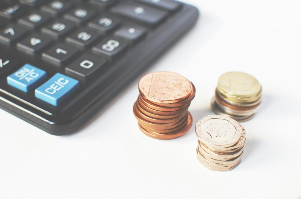 picture of a calculator next to three piles of coins